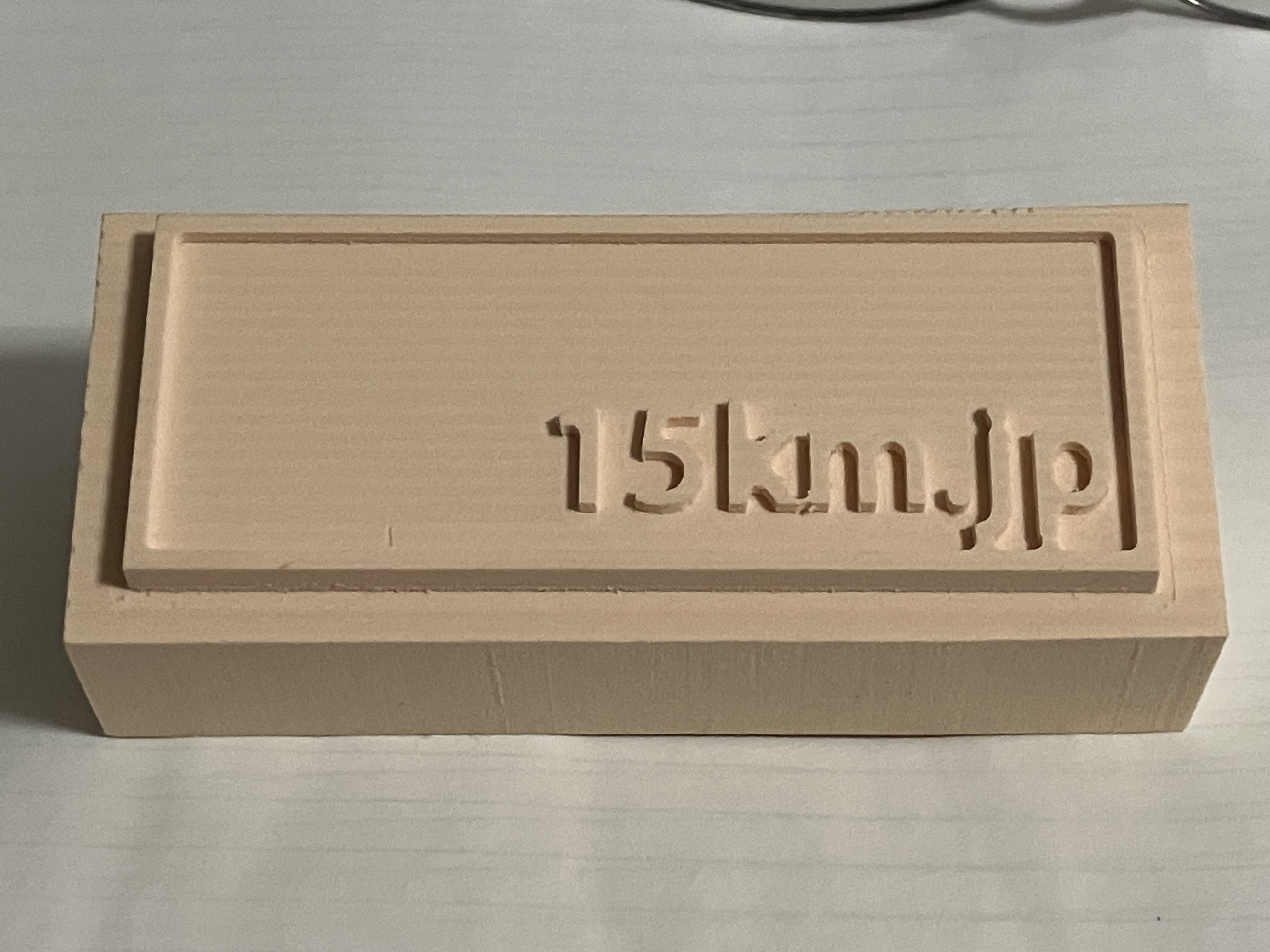 三次元加工の実習で木のチップのようなものに掘った15km.jpの文字