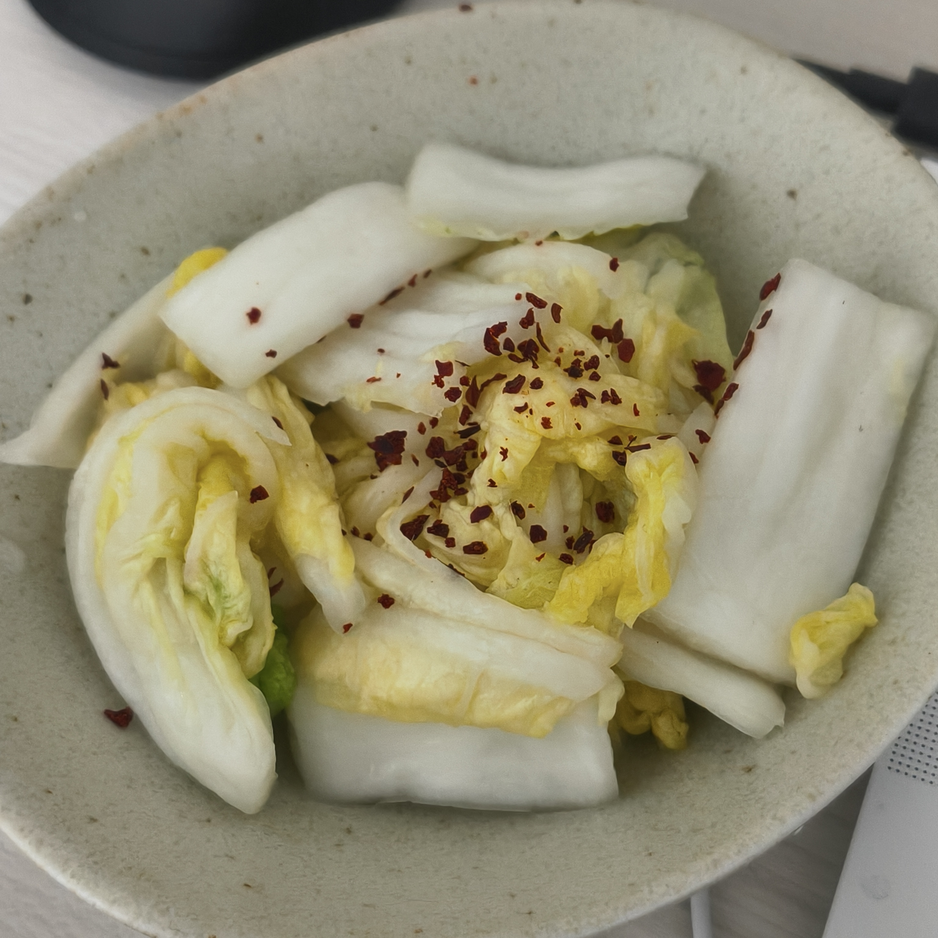 白い器に、塩漬けした白菜に粗挽きの韓国唐辛子が振られている。